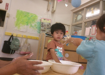 手についた小麦粉粘土を他の子に見せている様子