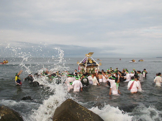 海の波しぶきを神輿が浴びています