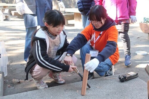 1:（画像）ジュニアリーダーに教えてもらいながら薪割り体験